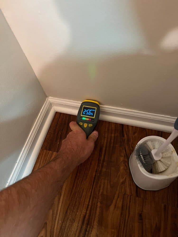 Moisture meter reading a baseboard during daily drying checks