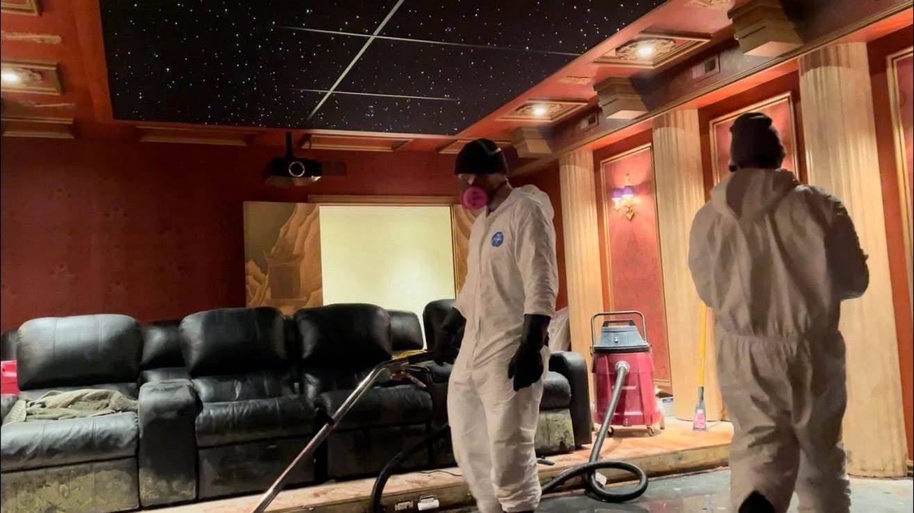 Flash techs in protective suits cleaning smoke-affected home theater seating — a real job