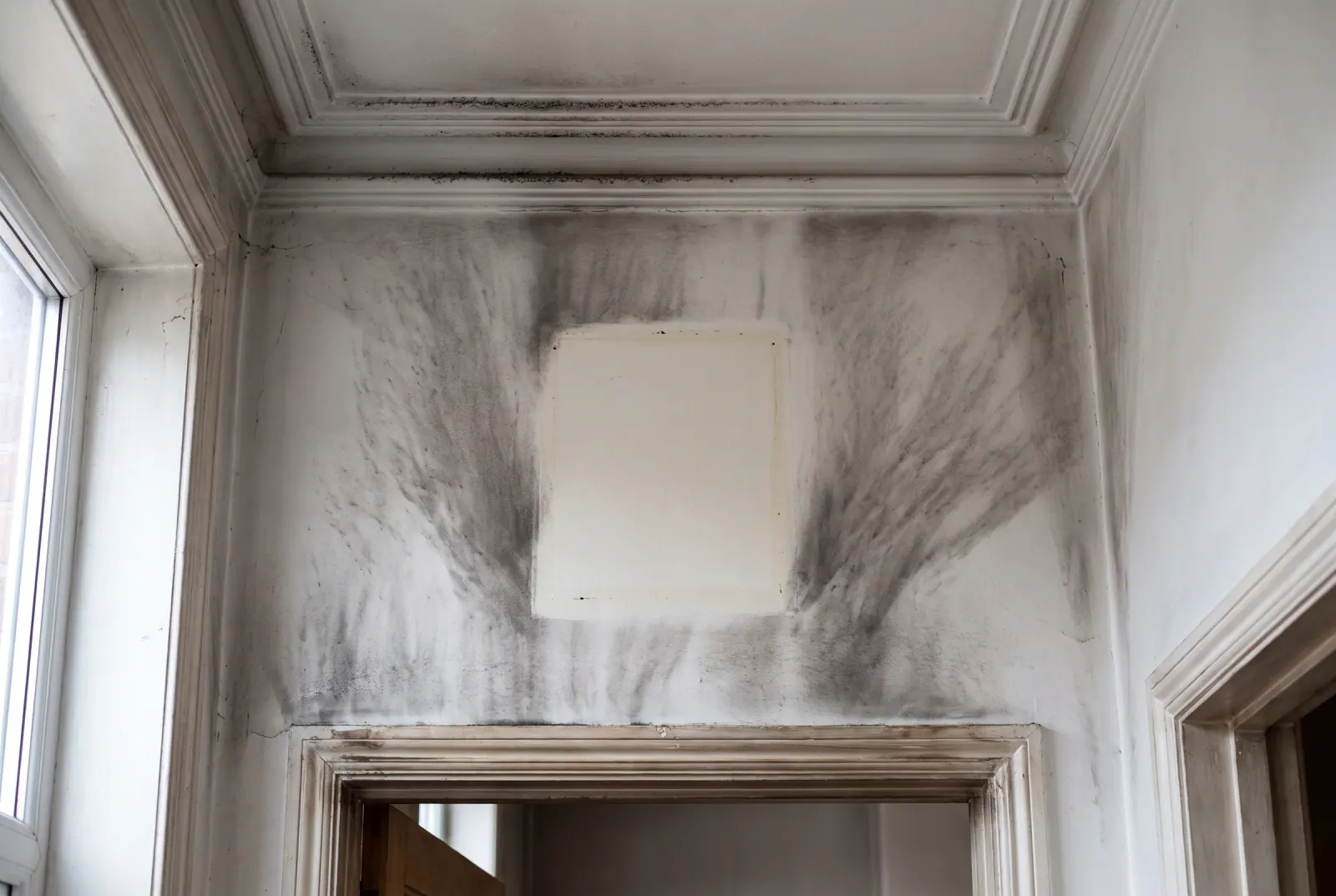 Smoke staining fanned across a wall corner, the residue soot cleaning removes